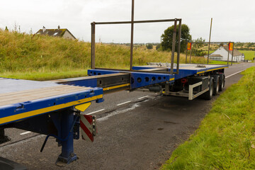 Blue HGV lorry truck extendable flatbed trailer being extended at roadside for wind turbine route test