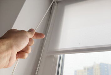 Photo of male hands using wand to close windows blinds