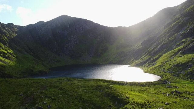 Aerial pull out shot of Llyn Cau lake from hiking path in Wales during a sunny day in the summer