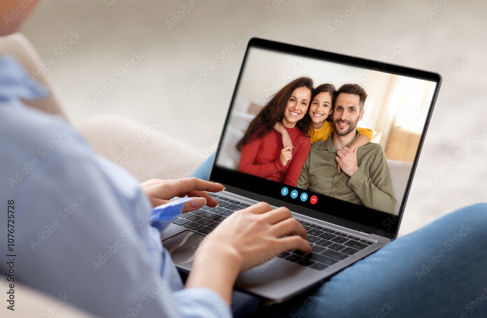 Poster A person is engaged in a video call with family members, smiling warmly while seated in a comfortable living area, creating a moment of connection and joy.