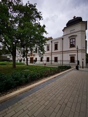 Obraz premium Historic building surrounded by greenery in a tranquil park setting on a cloudy day