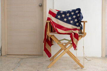 A wooden chair with a red, white, and blue American flag draped over it