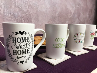 Inspirational coffee mugs on table with homemade cookies