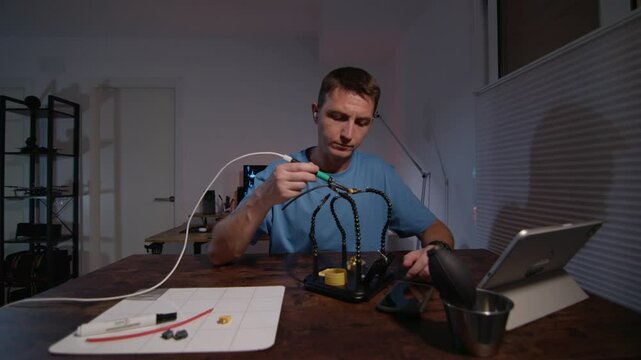 A man is Soldering electronics parts in home workshop