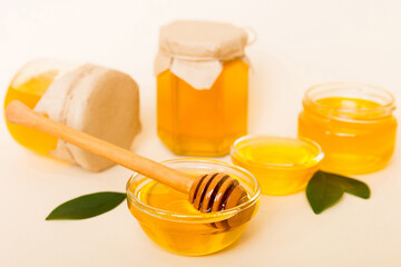 Honey in jar with leaves and honey dipper on colored background top view with copy text