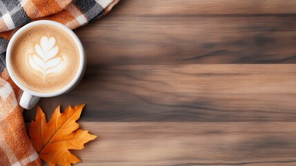 Naklejka premium A single autumn leaf laid beside a smooth latte adorned with art, all set in an elegant cup, wrapped gently with a plaid over a wood surface.