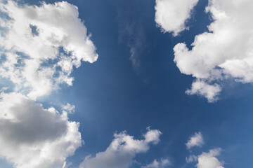 A piece of blue sky in the center of the frame, surrounded by summer cumulus clouds, copy space.
