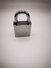 Fototapeta premium A close-up view of a shiny silver padlock on a plain background, symbolizing security and protection of personal belongings