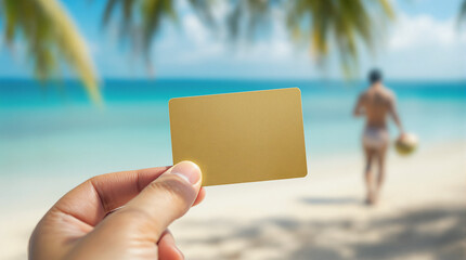 This image shows a hand holding a blank gold card on a tropical beach, with a blurred figure walking towards the ocean. Ideal for themes related to travel, luxury, and leisure.

