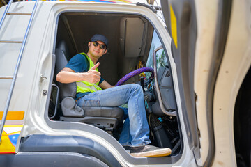 A truck driver in a reflective vest gives the thumbs up from the driver's seat during a major truck...