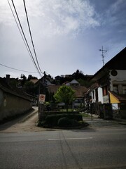 Scenic view of a quiet village with houses on a hillside under a cloudy sky in early afternoon
