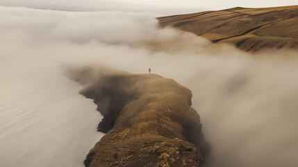 A person stands on a mountain top in the fog. The fog is thick and the mountain is covered in rocks. The person is looking out over the landscape, taking in the beauty of the scene