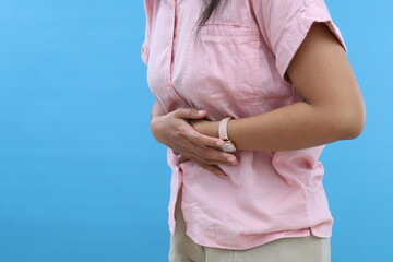 Woman has stomachache isolated over blue background with copyspace