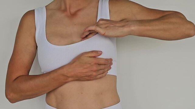 Breast cancer checking. Woman checking her breast on white background