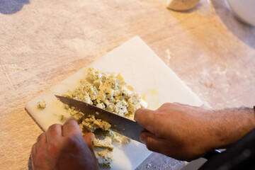 Chef chopping blue cheese for his restaurant recipe. Copy space, close up.