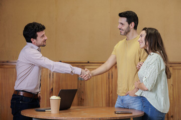Teacher meets with parents and shakes their hands in greeting and cordiality.