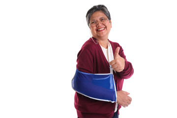 Happy woman with a blue arm sling, giving a thumbs up, smiling brightly, isolated on white...