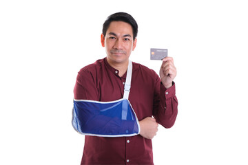 Man with arm in sling holding a credit card, isolated on white background.