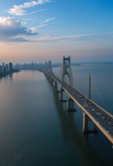 Fototapeta premium An expansive bridge stretches across a vast body of water under a calm blue sky.