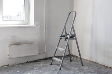 A folding ladder, a metal folding ladder in the room where the renovation is being done.