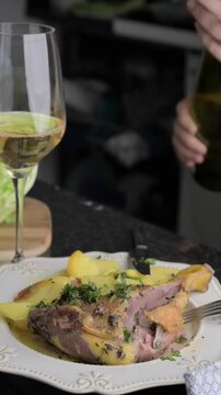 Roasted Duck Leg with Herbs and White Wine Gourmet Dining Experience. Succulent roasted duck leg seasoned with fresh herbs and paired with potatoes, served alongside a glass of white wine. 