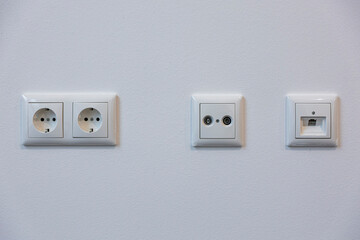 Power outlets, a TV cable connection, and a plan connection on a modern wall panel, offering essential connectivity for home entertainment and functionality.