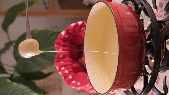 Cozy Swiss fondue setup with melted cheese, bread, pickles, and wine on a rustic table. advertising, social media campaigns, or food-related promotions. High quality 4k footage