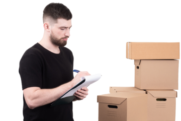 A man taking inventory with a clipboard beside stacked cardboard boxes, highlighting logistics, warehouse management, and organization in a storage setting.
