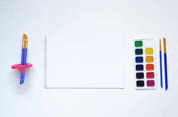 Top view of watercolors in a container and brush. Palette and shades of paint colors. Background with brush and paint for drawing.