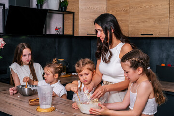 A young mother cooks a sweet cottage cheese pie with her daughters. Mom teaches her daughters to cook.