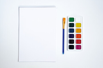 Top view of watercolors in a container and brush. Palette and shades of paint colors. Background with brush and paint for drawing.