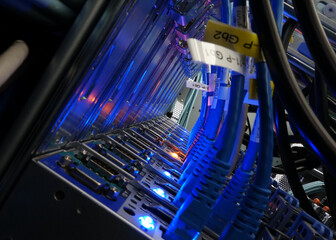 close up of network cables connected to server racks in data center room.