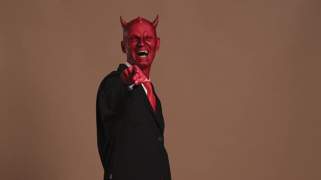 Businessman wearing devil horns costume pointing finger accusingly