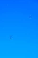 Round soap bubbles flying through the air with blue sky as background, children playing with soap...