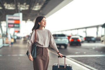 Standing tourist woman with travel luggage waiting at bus terminal for transport on day