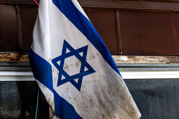 Mud stained, wrinkled blue and white flag of the State of Israel.