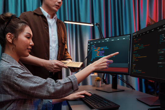 IT developers discussing with point to intelligent website development coder system running data online two screens information technology at neon light room at modern office. Infobahn.