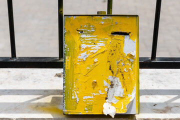 Yellow, aged, tzedakah box for collecting coins for charity, mounted to an iron fence in a religious neighborhood of Jerusalem, Israel.