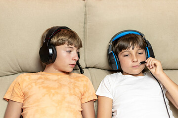 Close-up portrait of two children adjusting headphones on the sofa at home