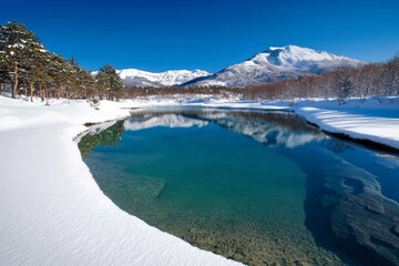 Fototapeta premium Mountain landscape with a clear blue lake reflecting snowy peaks, and pine trees lining the shore