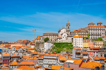 Obraz premium Colorful facades with traditional Portuguese glazed tile in Old town of Porto, Portugal. View of roofs, buildings and The Clérigos Church bell Tower (Igreja dos Clérigos) of Porto.