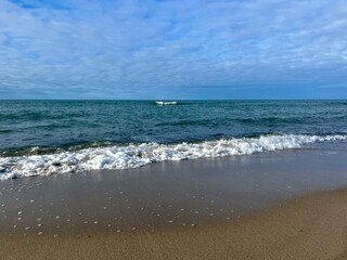 blue seascape, sandy shoreline, white clouds at the sky, seashore