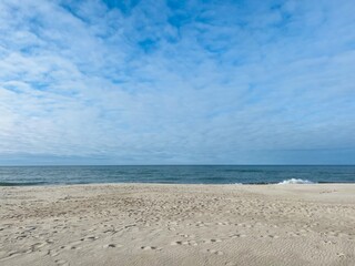 Blue sea horizon, blue sky with white clouds, sandy seashore, wild empty beach
