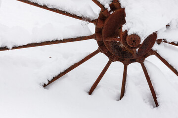 The rusty spokes and center of an old farm hay rake wheel is covered from a December snowfall within the Pike Lake Unit, Kettle Moraine State Forest, Hartford, Wisconsin.