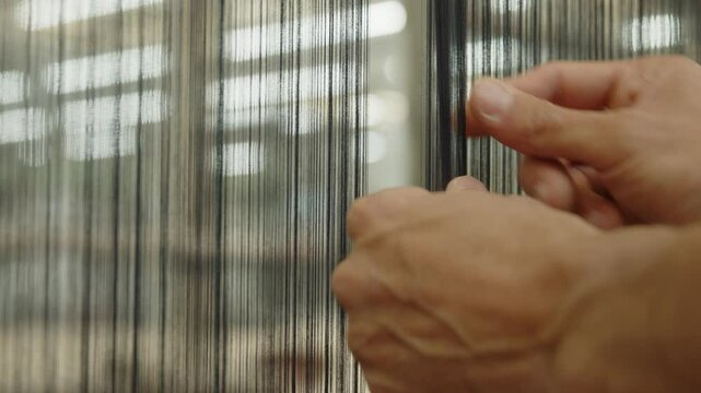 Worker's hands check the quality of the thread that creates fabric in a textile factory