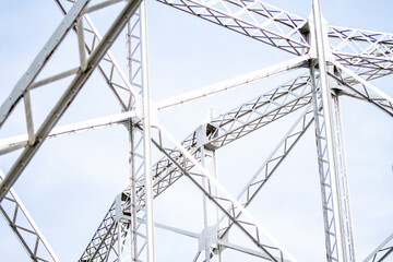 Detailed view of a metal truss structure with beams and crisscross patterns. Close-up of metal truss framework with intersecting beams against a light sky