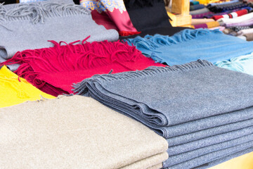 The warm scarves of various colors are on display for sale at the market stall.