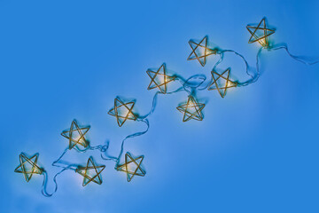 Golden metal garland with lights on blue background with copy space