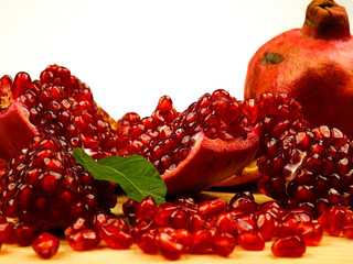 Whole and peeled ripe fresh pomegranates against a white background