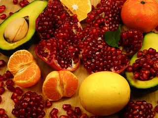 Fresh ripe fruits, vitamin product set. Pomegranates, lemons, avocado and tangerines lie on a wooden board